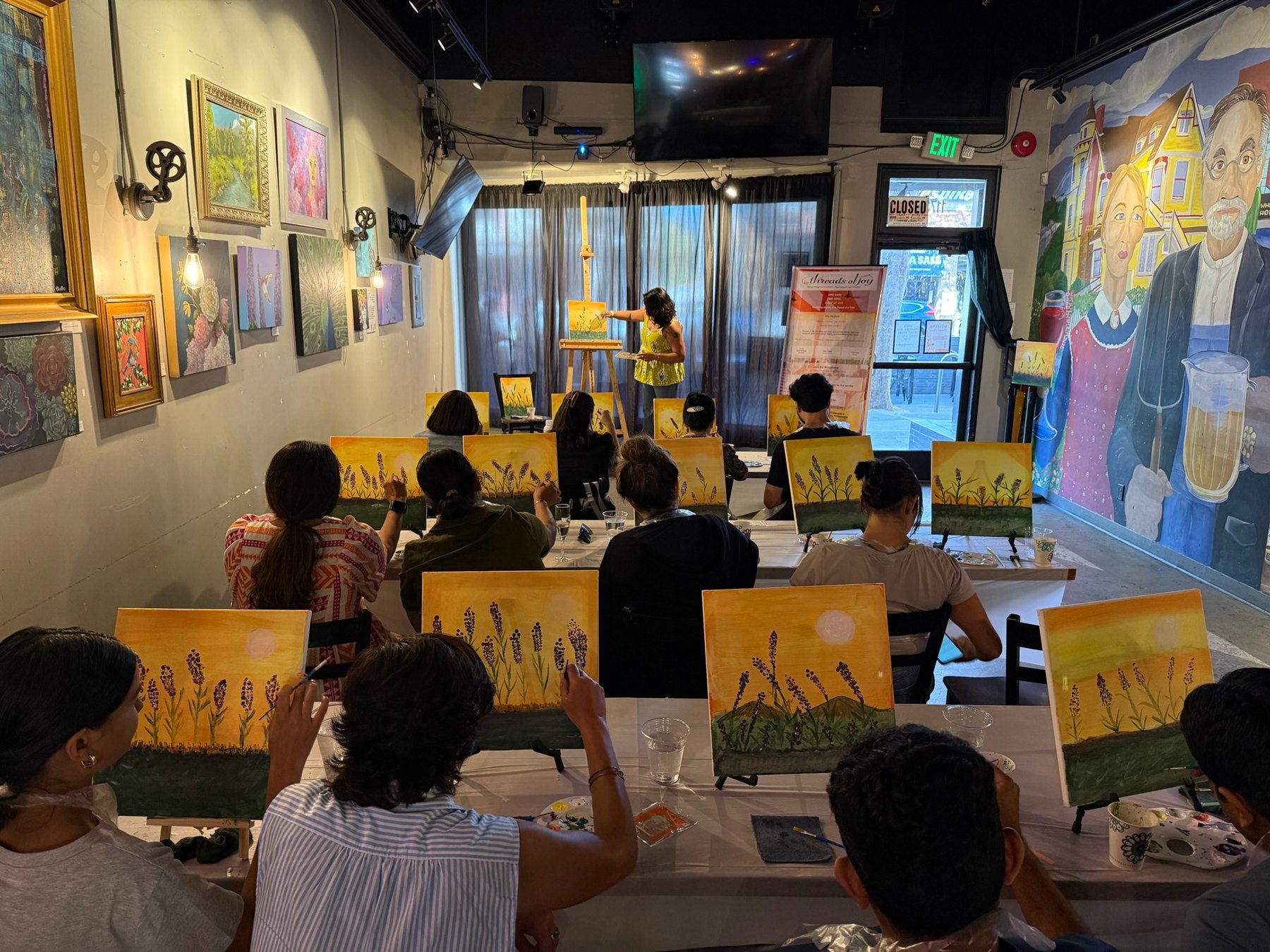 Brush Hour participants follow along with the instructor while painting golden field scenes.