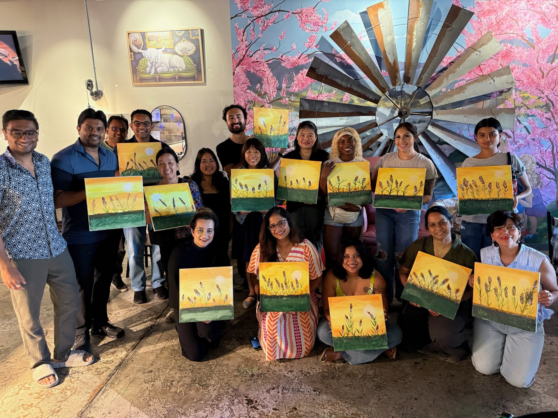 Brush Hour participants pose together with their completed paintings.