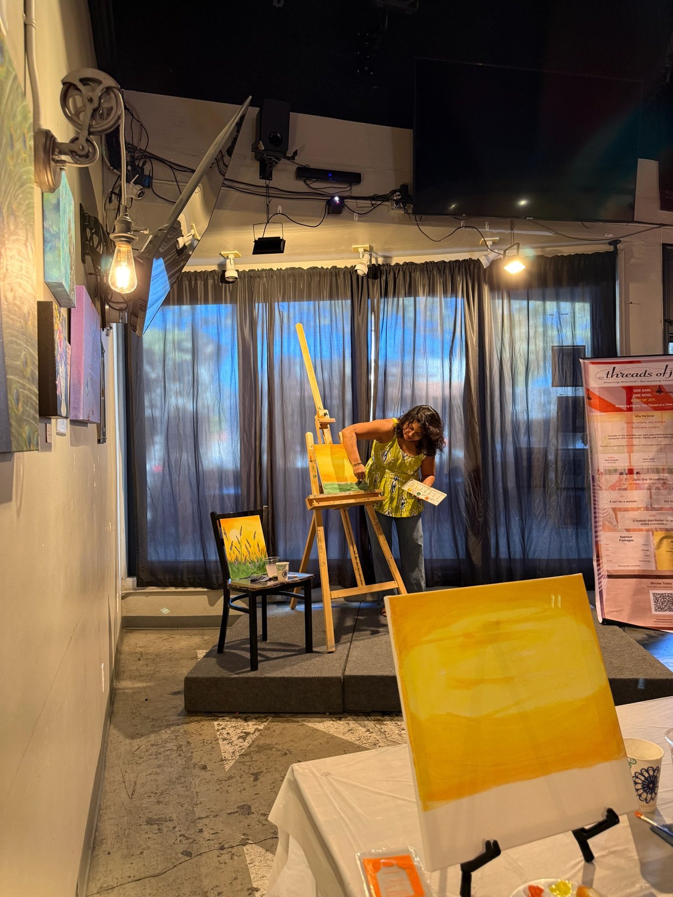 The Brush Hour instructor demonstrates a painting technique at the front of the room.